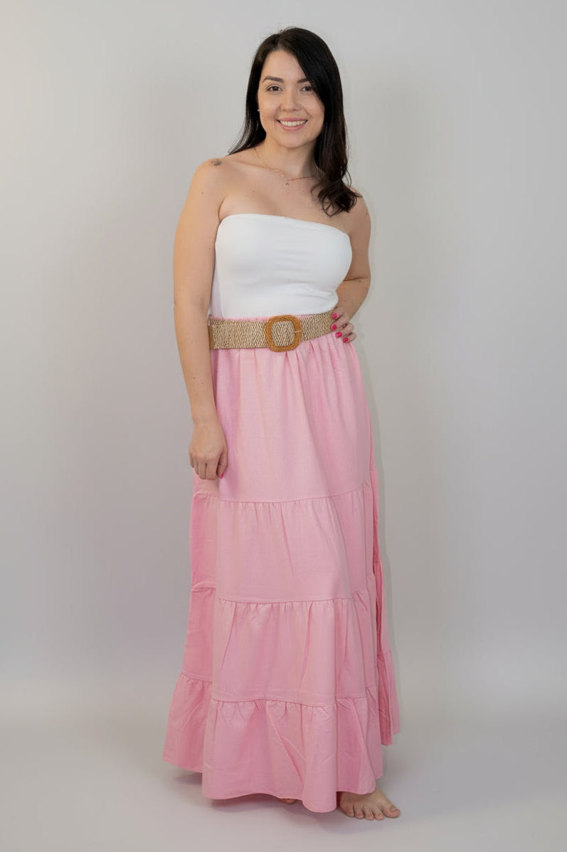 Woman wearing a white top and pink skirt with a belt against a white background