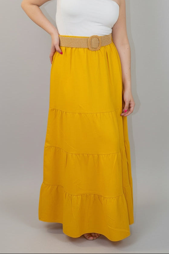 Woman wearing a white top and yellow skirt with a belt on a white background