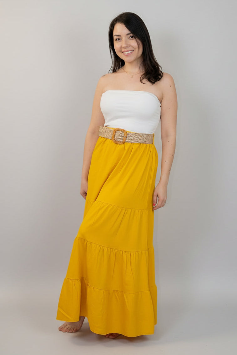 Woman wearing a white top and yellow skirt with a belt on a white background