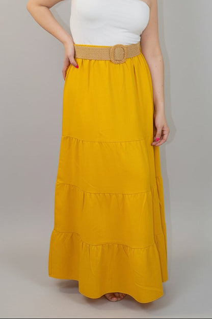 Woman wearing a white top and yellow skirt with a belt on a white background