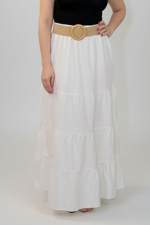 Woman wearing a black top and white skirt with a gold belt on a white background