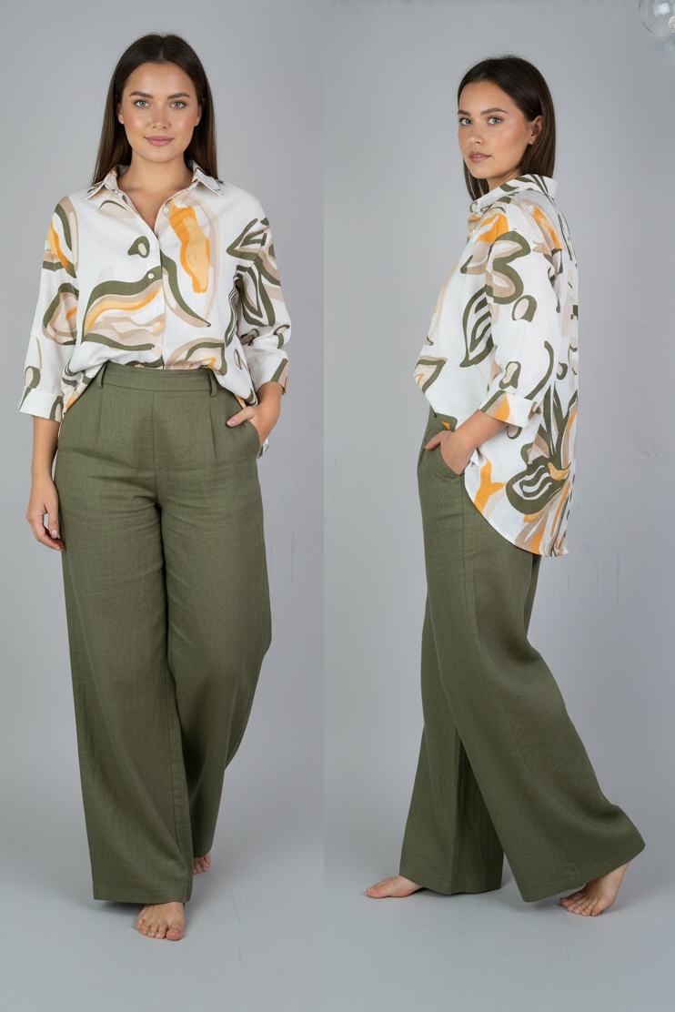 Woman wearing a patterned blouse and green pants against a gray background