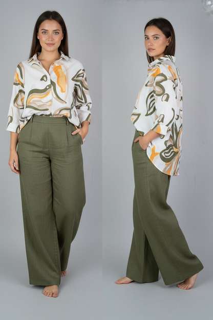 Woman wearing a patterned blouse and green pants against a gray background