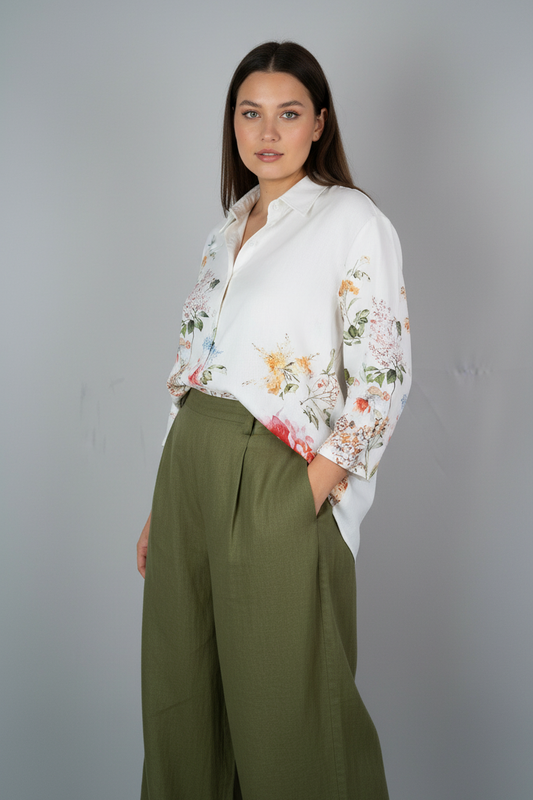 Woman wearing a floral blouse and green pants against a gray background